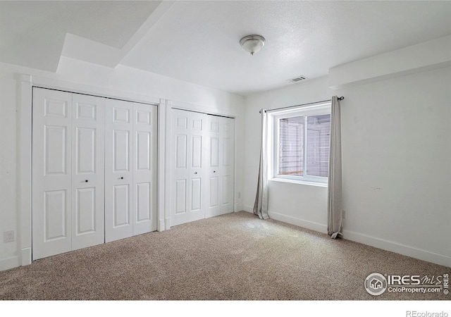 unfurnished bedroom featuring carpet flooring and multiple closets