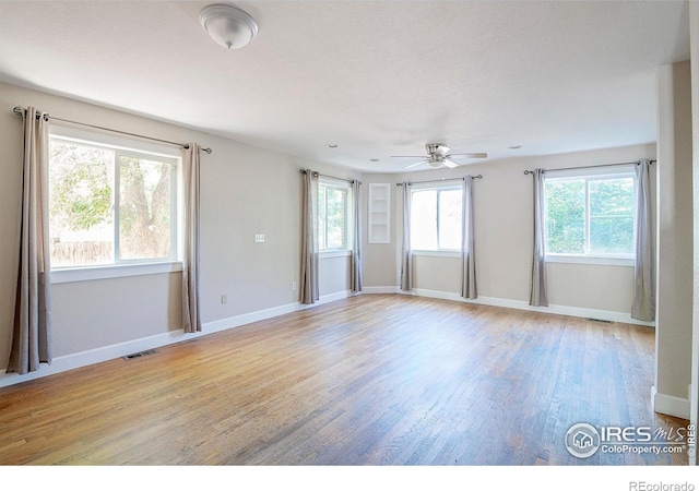 empty room featuring light hardwood / wood-style floors, a wealth of natural light, and ceiling fan