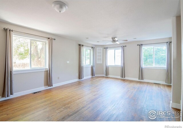 empty room featuring ceiling fan, a healthy amount of sunlight, and light hardwood / wood-style flooring