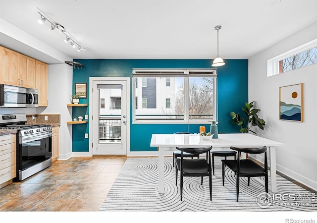 kitchen featuring light brown cabinetry, hanging light fixtures, and stainless steel appliances