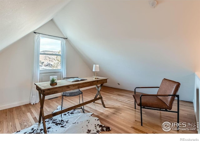 office featuring lofted ceiling and light hardwood / wood-style flooring