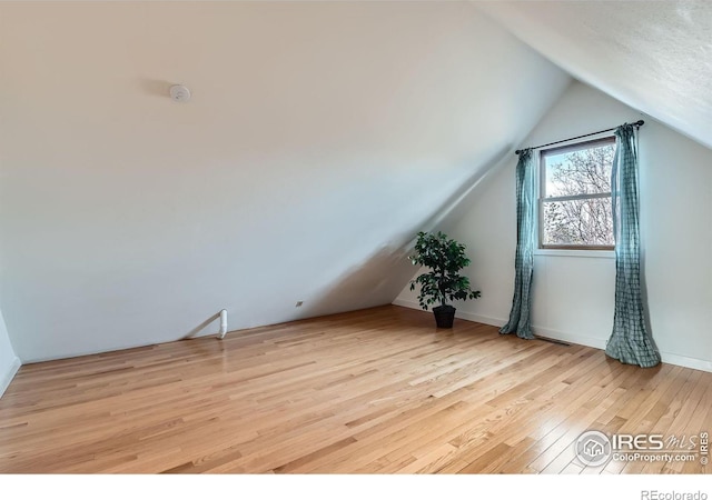 bonus room featuring vaulted ceiling and light wood-type flooring