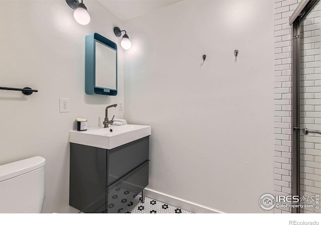 bathroom featuring tile patterned flooring, vanity, a shower with shower door, and toilet