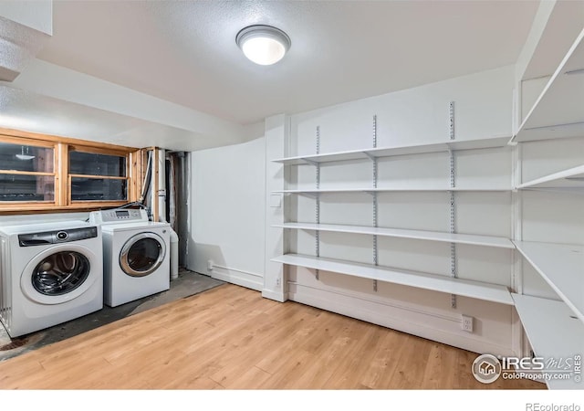 clothes washing area with washer and dryer and hardwood / wood-style flooring