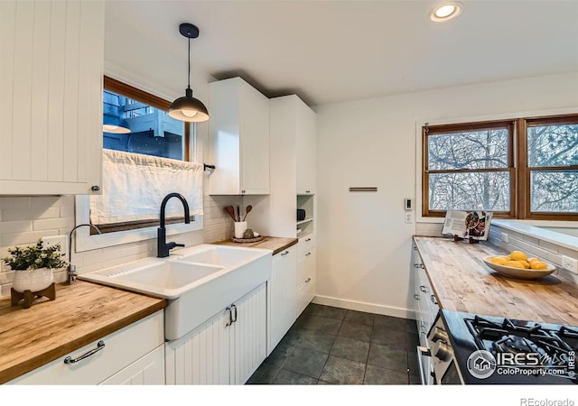 kitchen featuring pendant lighting, wood counters, white cabinets, and backsplash