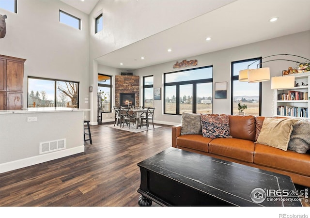 living room featuring a fireplace, dark hardwood / wood-style flooring, and a towering ceiling