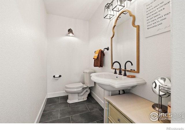 bathroom with baseboards, a sink, toilet, and tile patterned floors