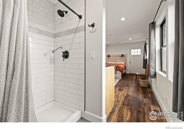 ensuite bathroom with baseboards, connected bathroom, wood finished floors, a tile shower, and recessed lighting