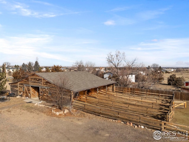 exterior space featuring roof with shingles, an outdoor structure, and an exterior structure