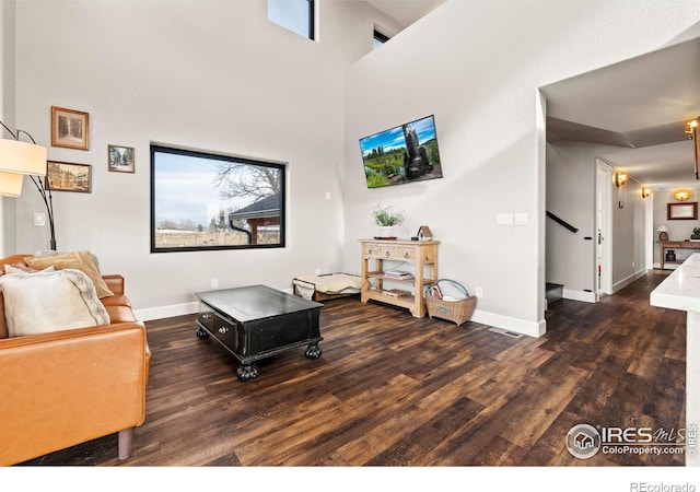 living area with a high ceiling, baseboards, and wood finished floors