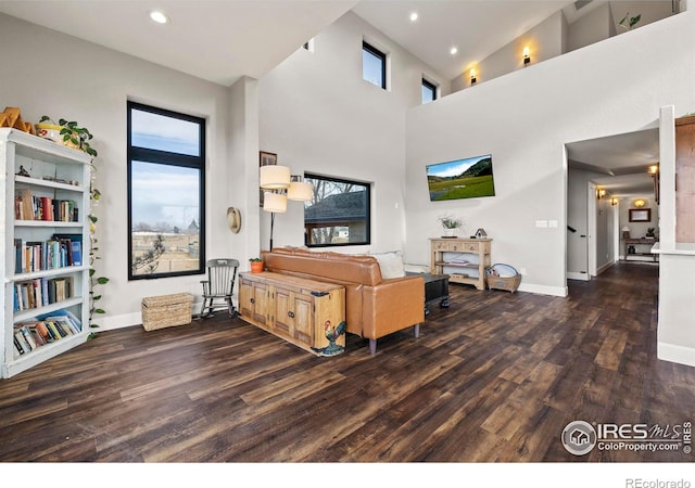 living room with a high ceiling, recessed lighting, wood finished floors, and baseboards