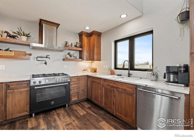 kitchen with dark wood-type flooring, stainless steel appliances, wall chimney range hood, open shelves, and a sink