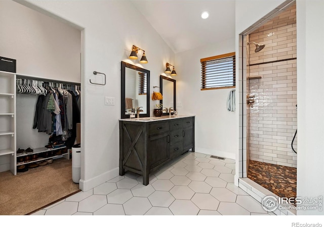 full bath with visible vents, tiled shower, lofted ceiling, tile patterned floors, and vanity