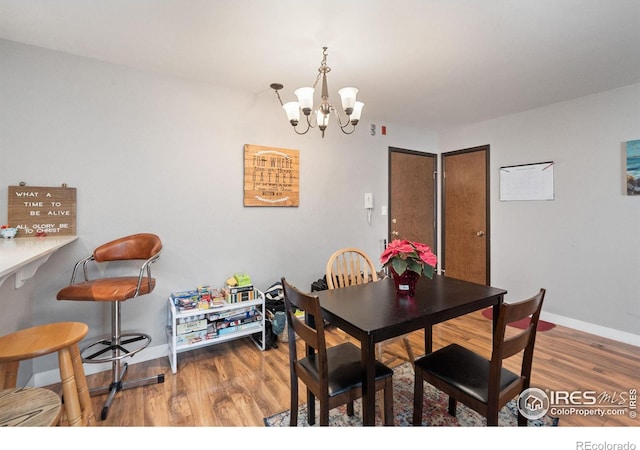 dining space with wood-type flooring and a notable chandelier