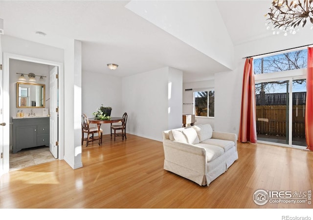 living room with a notable chandelier, light hardwood / wood-style floors, and sink