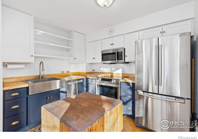 kitchen with white cabinets, sink, blue cabinets, and stainless steel appliances