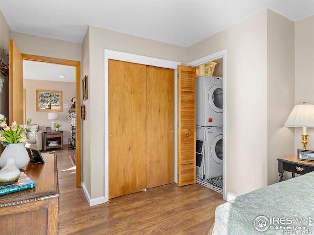 bedroom featuring hardwood / wood-style flooring, stacked washer and dryer, and a closet