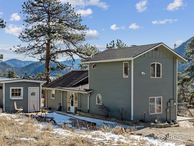 snow covered back of property featuring a mountain view