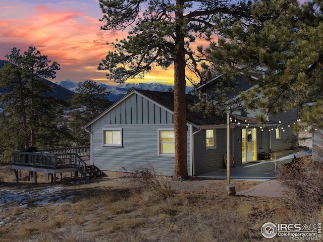 property exterior at dusk with a deck with mountain view and a patio area