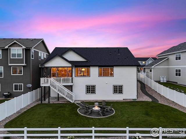 back house at dusk featuring a yard and an outdoor fire pit