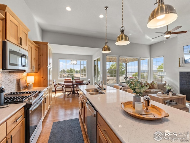 kitchen with pendant lighting, decorative backsplash, sink, and appliances with stainless steel finishes