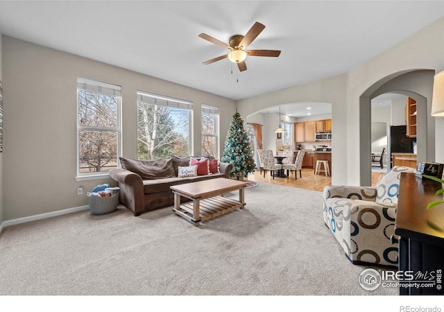 living room featuring a healthy amount of sunlight, ceiling fan, and light carpet