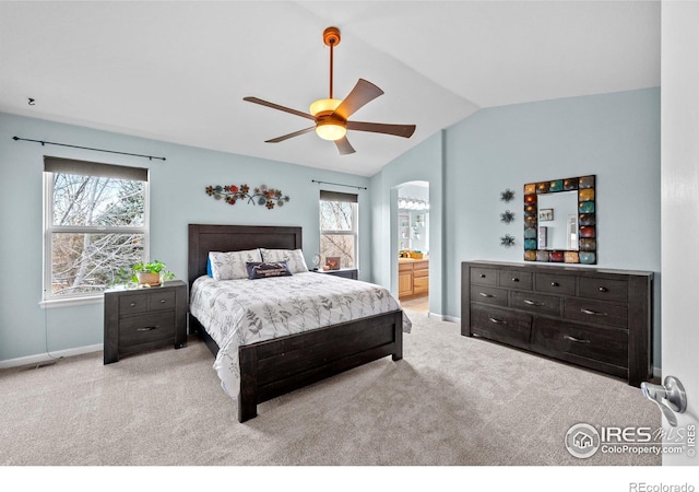 carpeted bedroom with multiple windows, connected bathroom, ceiling fan, and lofted ceiling