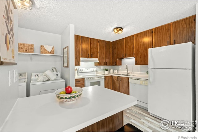 kitchen with white appliances, sink, light hardwood / wood-style flooring, washer and dryer, and a textured ceiling