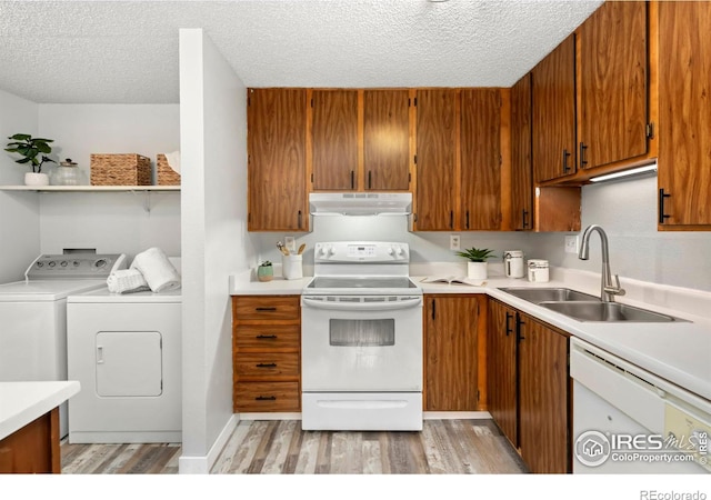 kitchen featuring sink, a textured ceiling, white appliances, washer and dryer, and light wood-type flooring