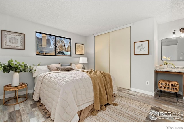 bedroom with dark hardwood / wood-style flooring, a textured ceiling, and a closet