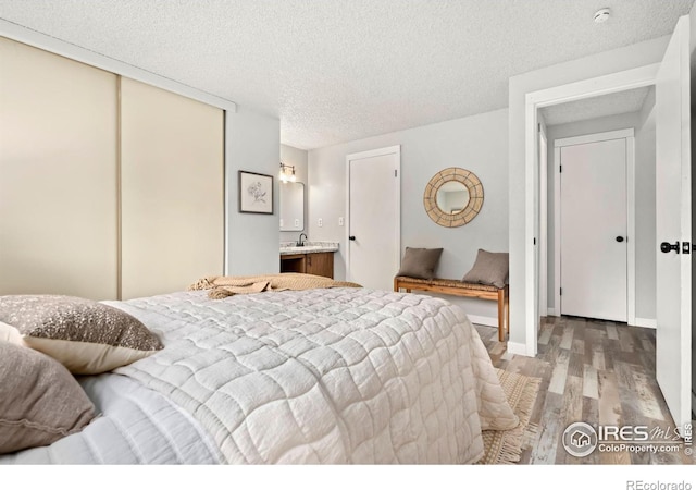 bedroom with sink, light wood-type flooring, a textured ceiling, and a closet