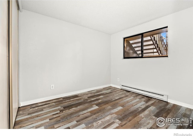 unfurnished room featuring dark hardwood / wood-style flooring and baseboard heating