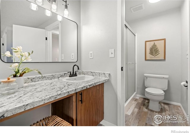 bathroom featuring vanity, hardwood / wood-style flooring, toilet, and walk in shower