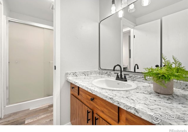 bathroom featuring hardwood / wood-style floors, vanity, and a shower with door