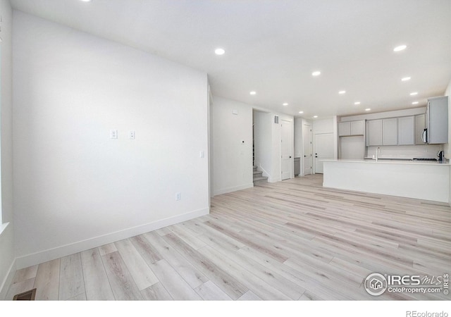 unfurnished living room with light hardwood / wood-style floors and sink