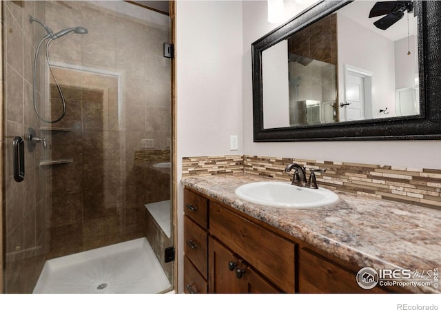 bathroom with ceiling fan, an enclosed shower, vanity, and tasteful backsplash