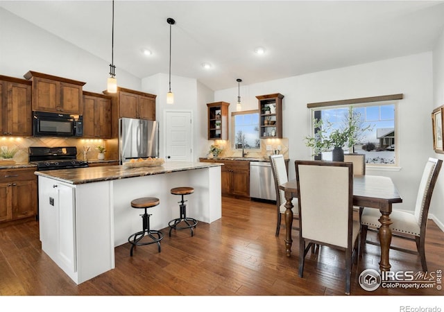 kitchen featuring decorative backsplash, hanging light fixtures, black appliances, and a center island