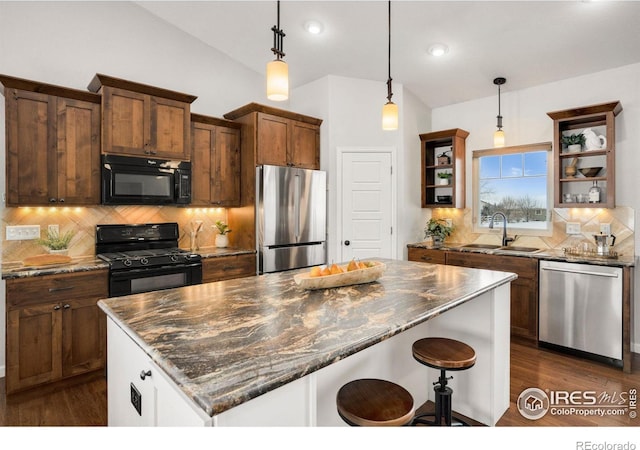 kitchen with sink, black appliances, decorative light fixtures, and dark stone counters