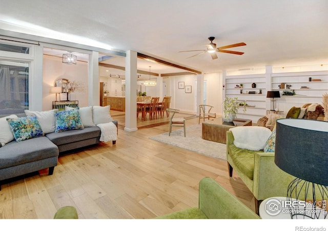 living room with hardwood / wood-style floors, ceiling fan with notable chandelier, and built in shelves