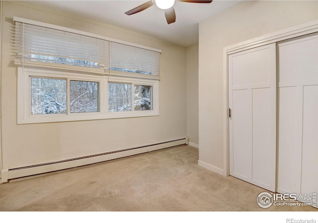 unfurnished bedroom with ceiling fan, a closet, light colored carpet, and a baseboard heating unit