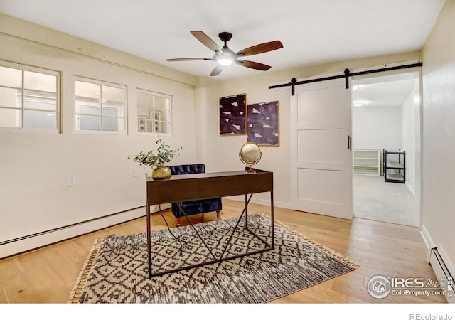 office space featuring a barn door, ceiling fan, wood-type flooring, and a baseboard heating unit