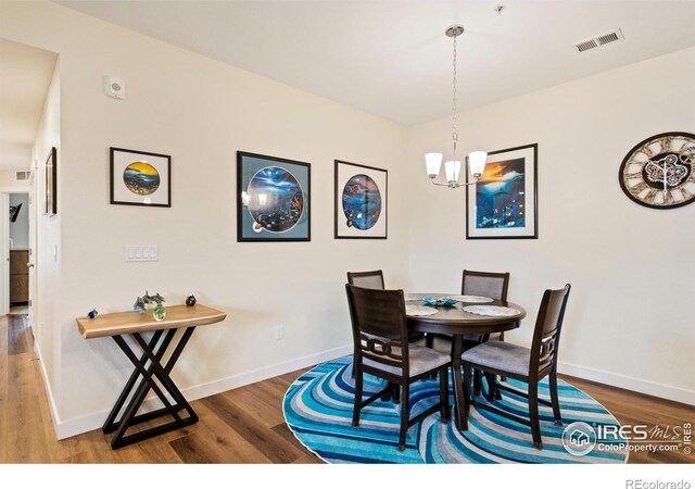 dining area with wood-type flooring and an inviting chandelier