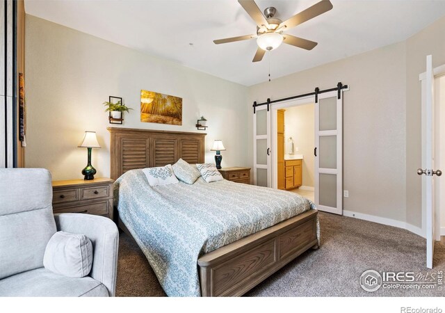 carpeted bedroom with a barn door, ensuite bath, and ceiling fan