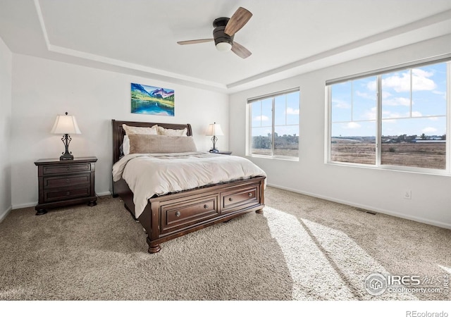 bedroom featuring ceiling fan, light carpet, and a tray ceiling