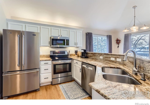 kitchen featuring light stone countertops, stainless steel appliances, sink, decorative light fixtures, and white cabinets