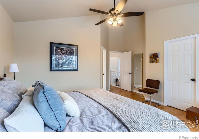 bedroom featuring light hardwood / wood-style floors, high vaulted ceiling, and ceiling fan