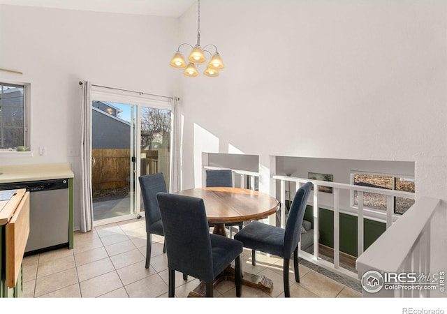 dining area featuring a towering ceiling, light tile patterned floors, and a notable chandelier