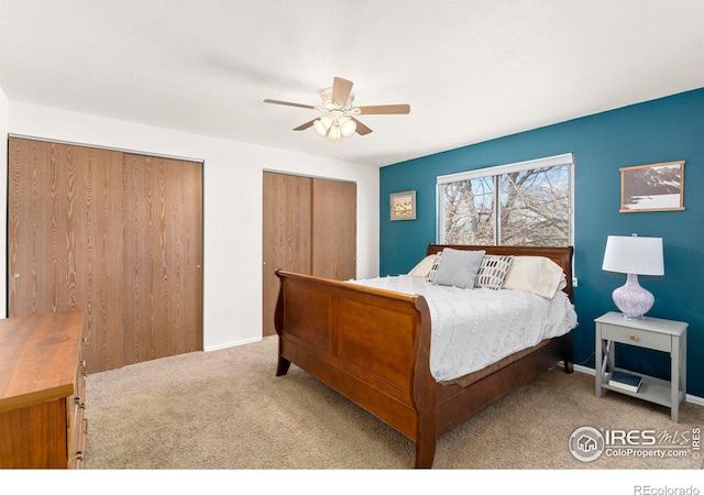 carpeted bedroom featuring ceiling fan and two closets