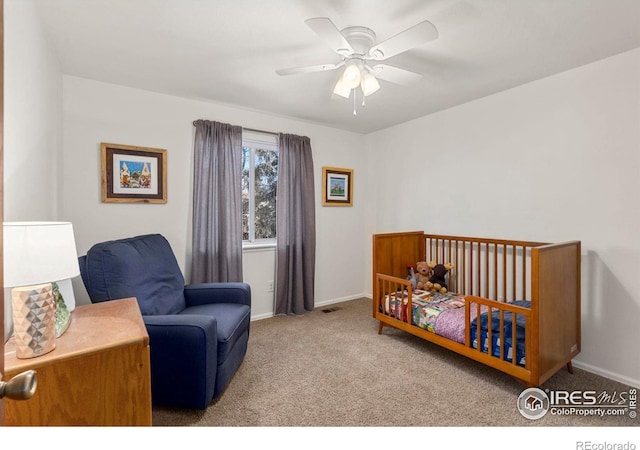 bedroom featuring light carpet, a crib, and ceiling fan