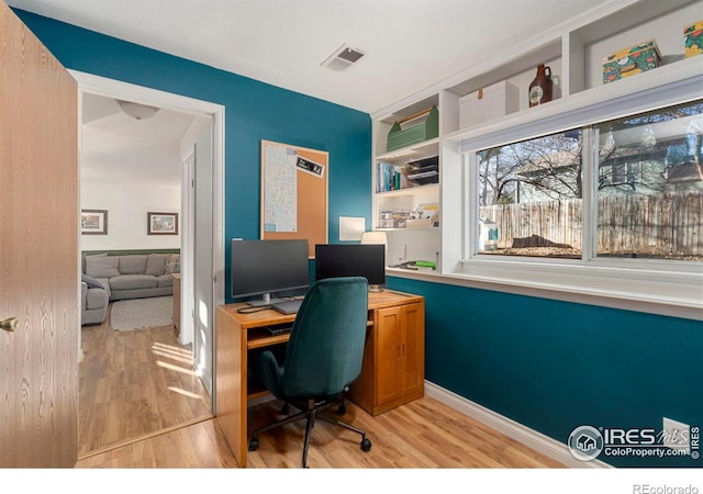 office space with built in shelves and light wood-type flooring